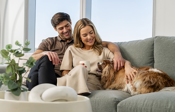 A couple sitting on the couch with their dog