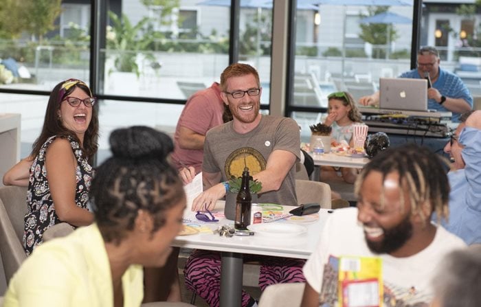 Residents laughing at resident event, sitting at tables playing a trivia game