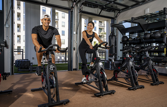 Two people cycling in a gym